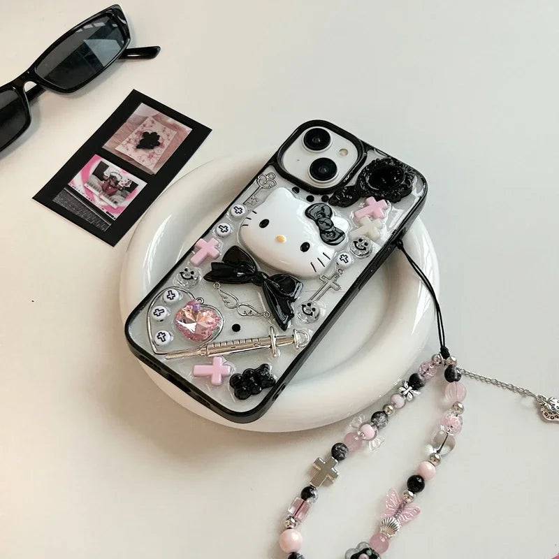 A Hello Kitty themed phone case with a black bow design, displayed alongside a box, sunglasses, and decorative beads.