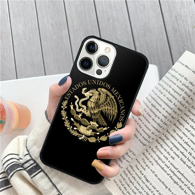 Phone case with Mexican coat of arms design held by a person on a wooden surface.