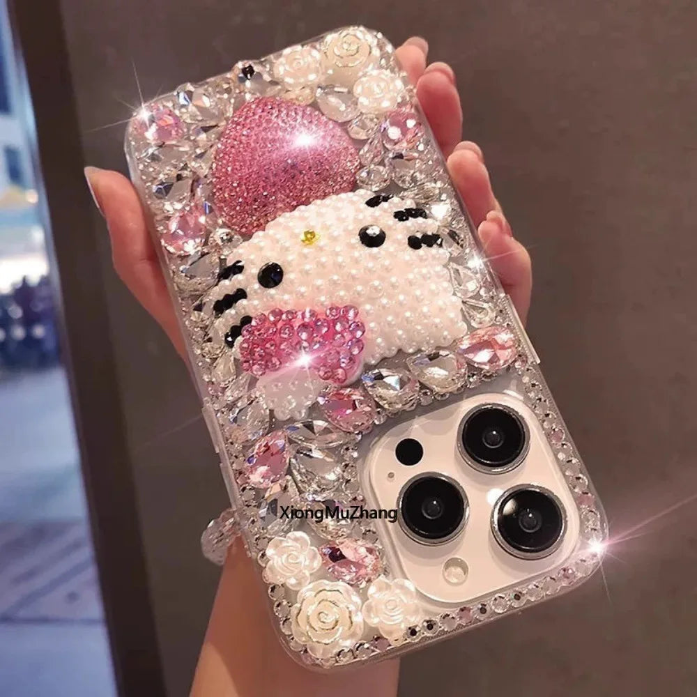 Phone case with a Hello Kitty design, decorated with crystals and rhinestones, held by a hand.