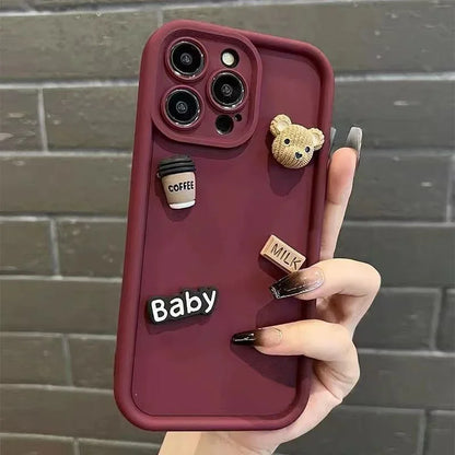 This image features a custom iPhone case with a playful 3D cartoon design. The case is predominantly white and showcases a series of raised elements including a bear, a camera, and text that reads "Baby" and "Milk".