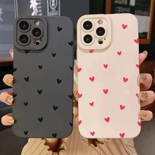 Two silicone phone cases, one black and one pink, each adorned with small heart patterns.