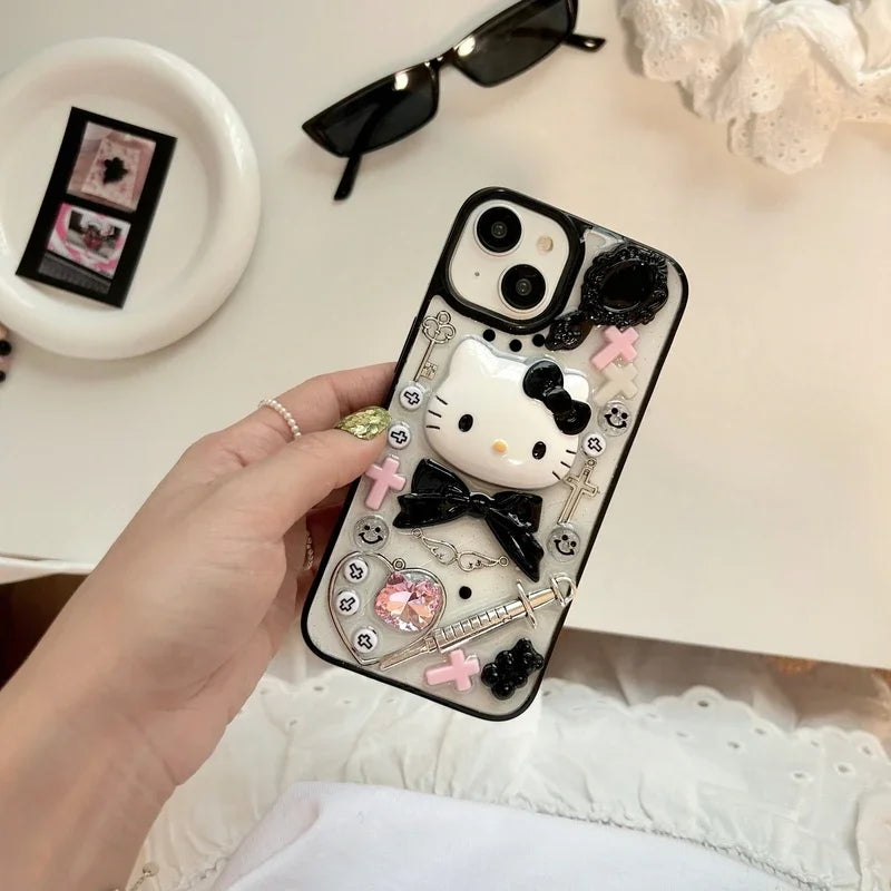 A Hello Kitty themed phone case with a black bow design, displayed alongside a box, sunglasses, and decorative beads.
